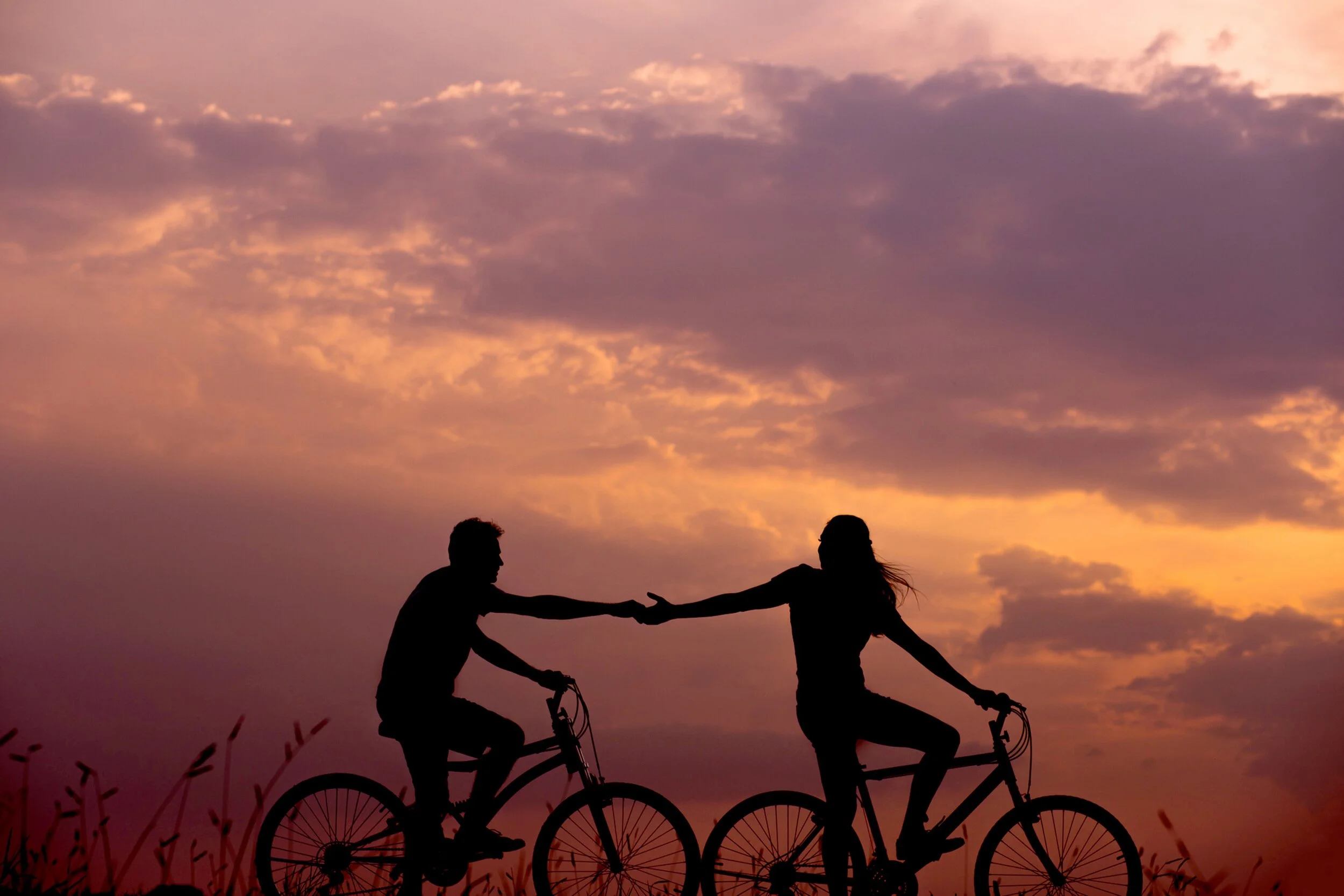 Silhouette of two people riding bicycles at sunset