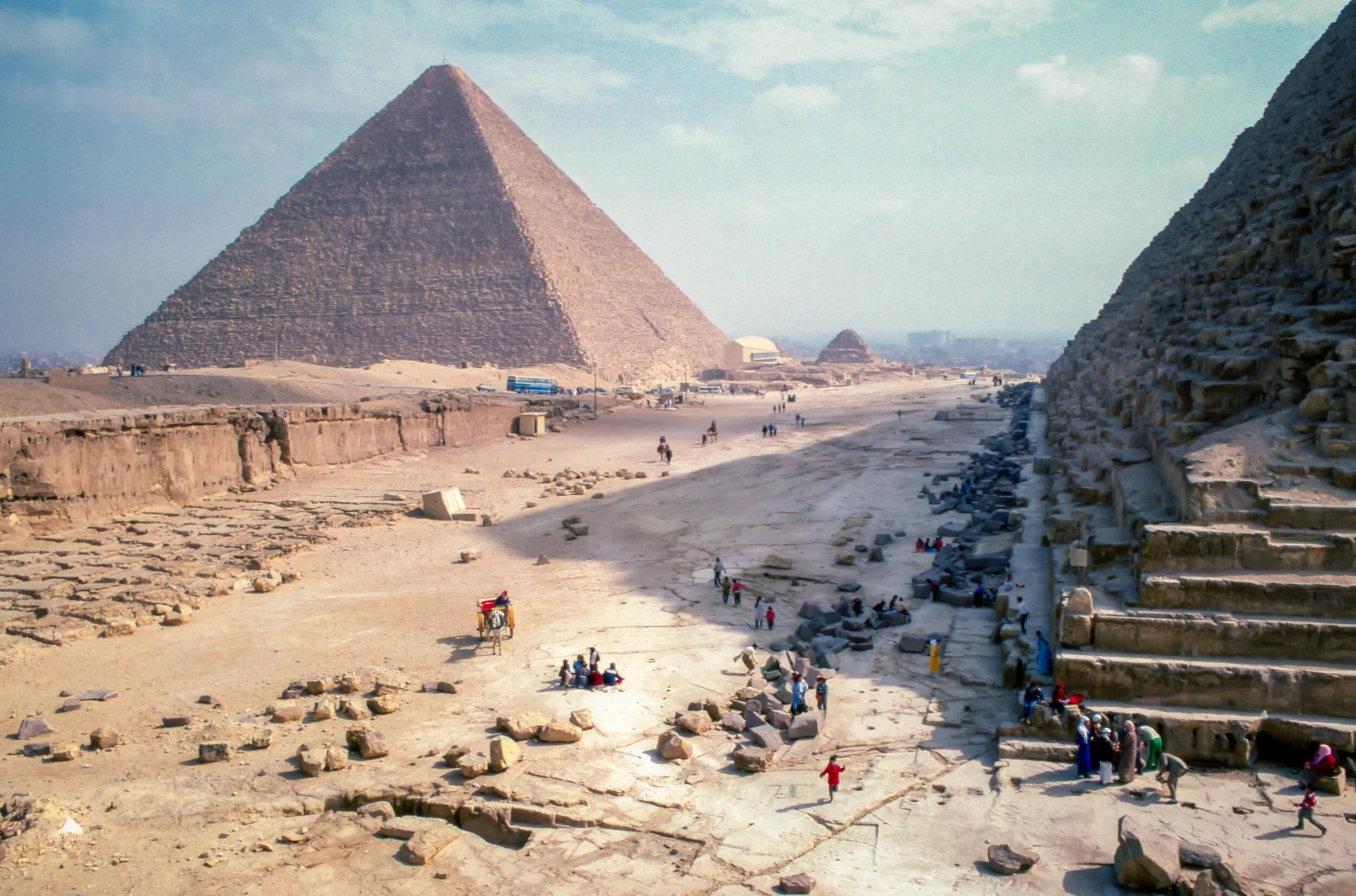 The Pyramids of Giza in Egypt, with people and camels in the foreground.