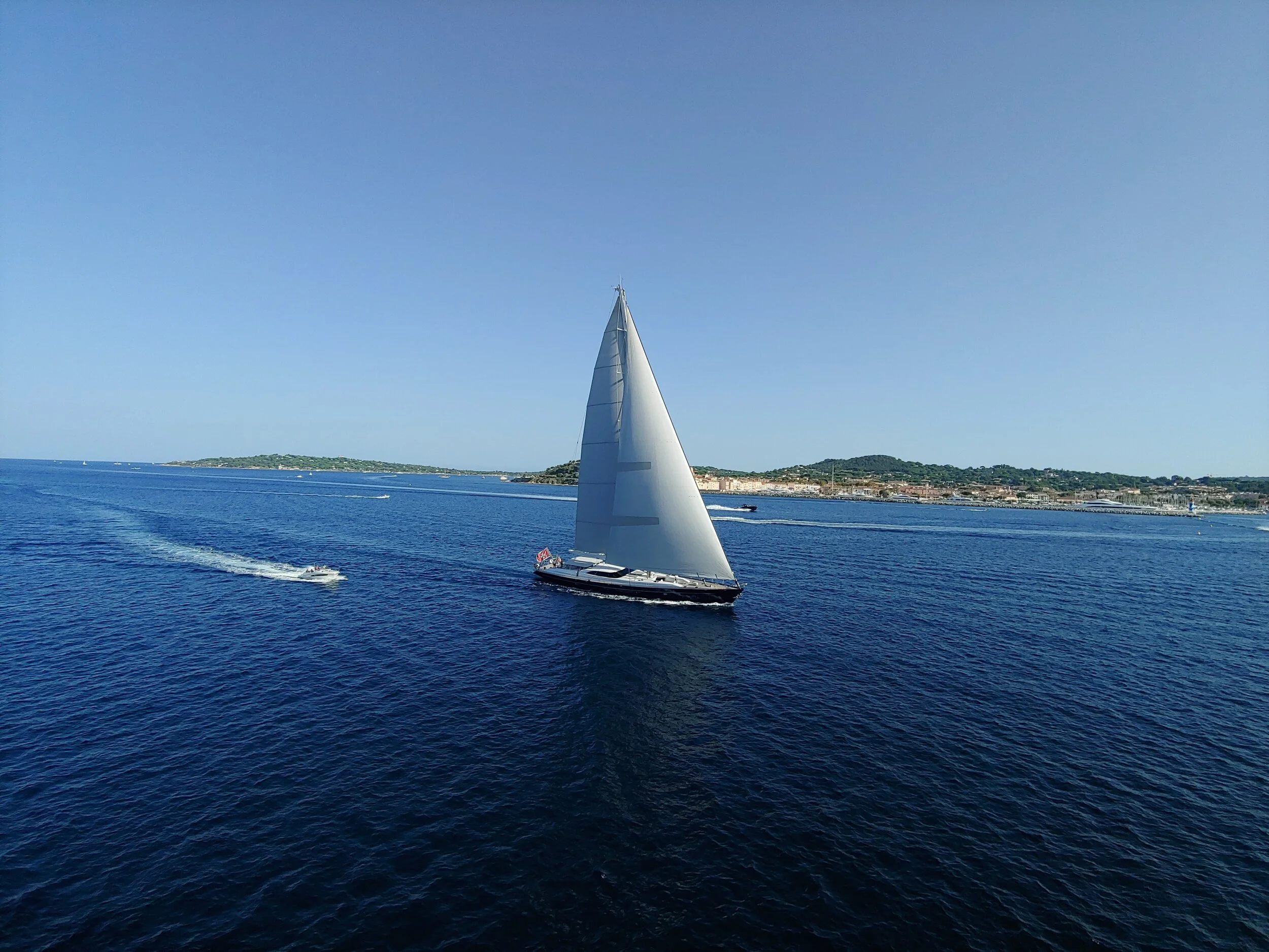 Sailboat on the ocean with distant coastline