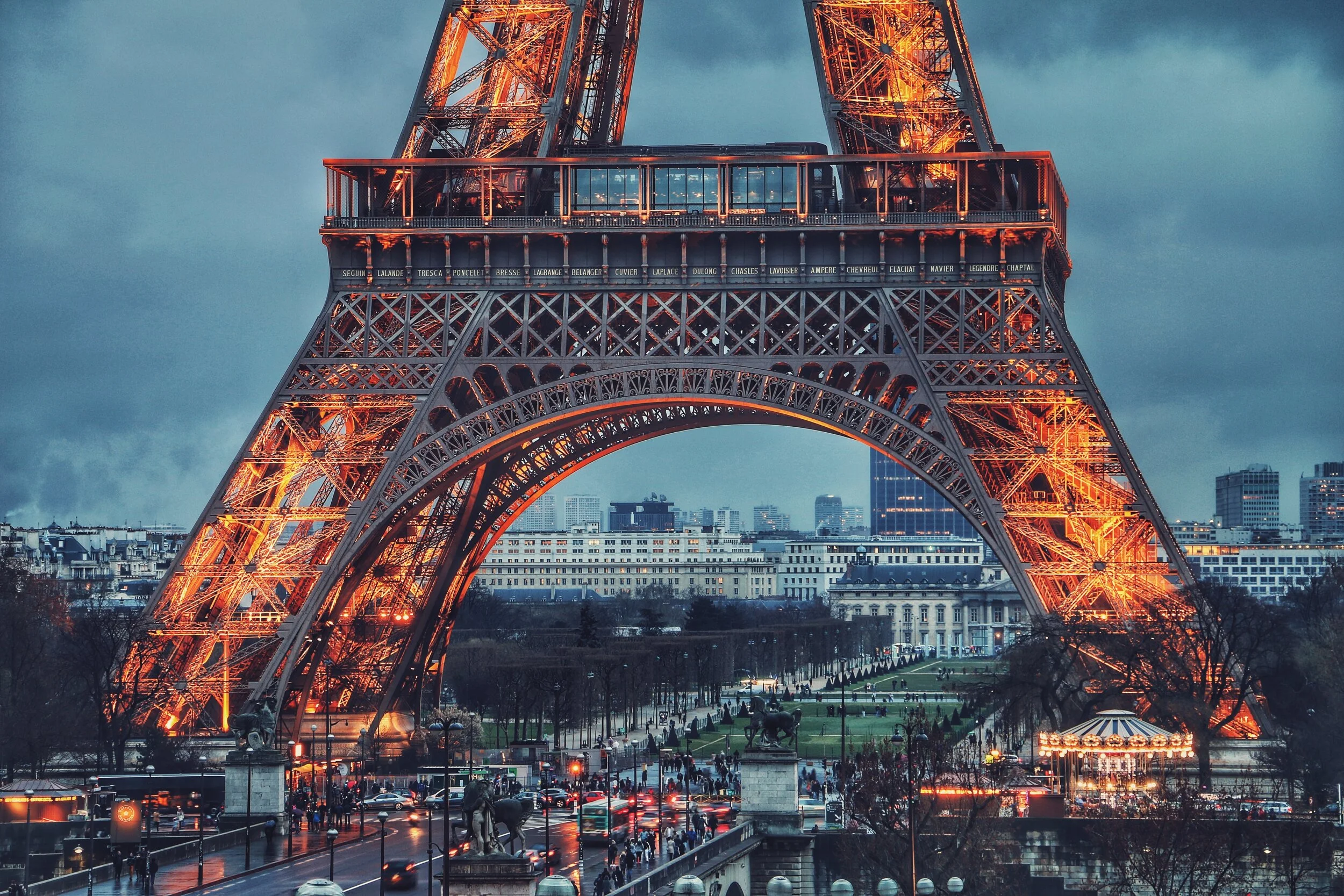 The Eiffel Tower illuminated at dusk with cityscape view and carousel.