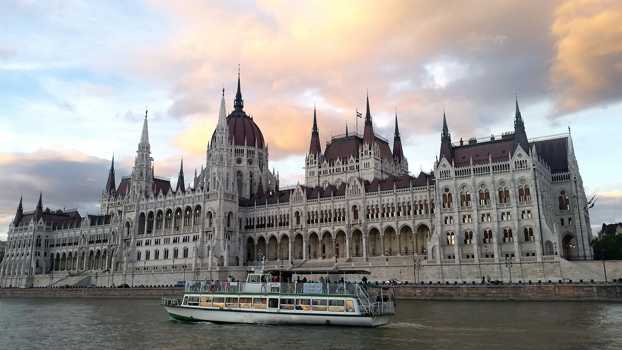 The Budapest Parliament building with a boat on the Danube River in front.
