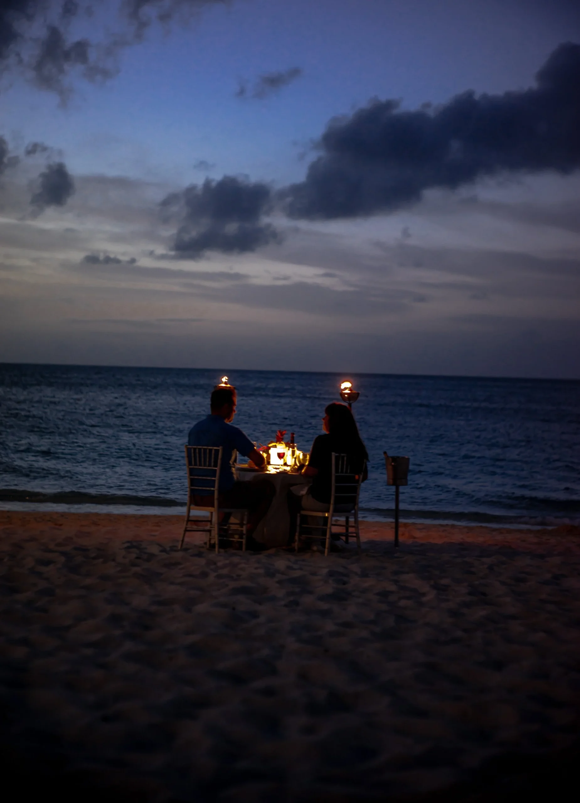 Couple having a romantic dinner on a beach at sunset.